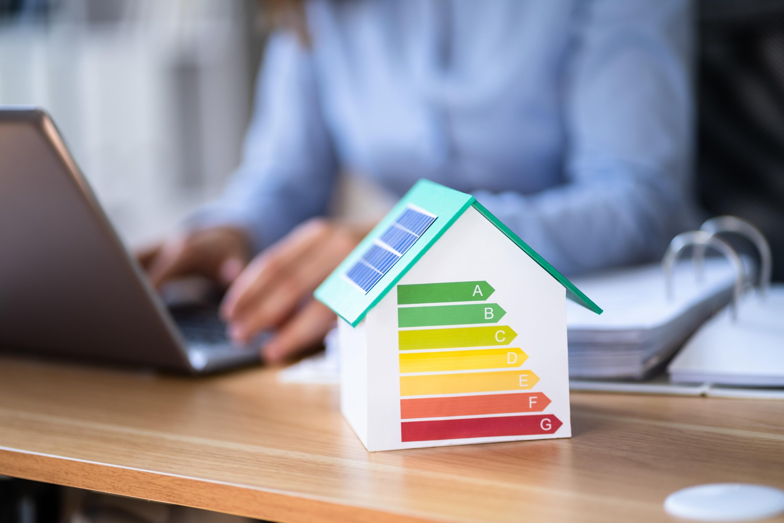 Modellhaus mit farbiger Energieeffizienz-Skala (A bis G) auf einem Schreibtisch während einer Energieberatung in der Region Hannover.
